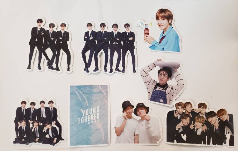 May include: A collection of stickers featuring a K-pop boy band. The stickers are printed on white paper and feature various images of the band members, including a group photo, individual portraits, and a photo of the band members holding a Coca-Cola bottle. The stickers also feature the text "Young Forever".