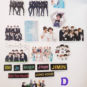 May include: A collection of stickers featuring the South Korean boy band BTS. The stickers feature various images of the band members, including individual portraits, group photos, and cartoon illustrations. The stickers are printed on white paper and have a glossy finish.