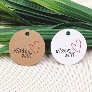 May include: Two round gift tags, one brown and one white, with a red heart and the text "made with" in black.