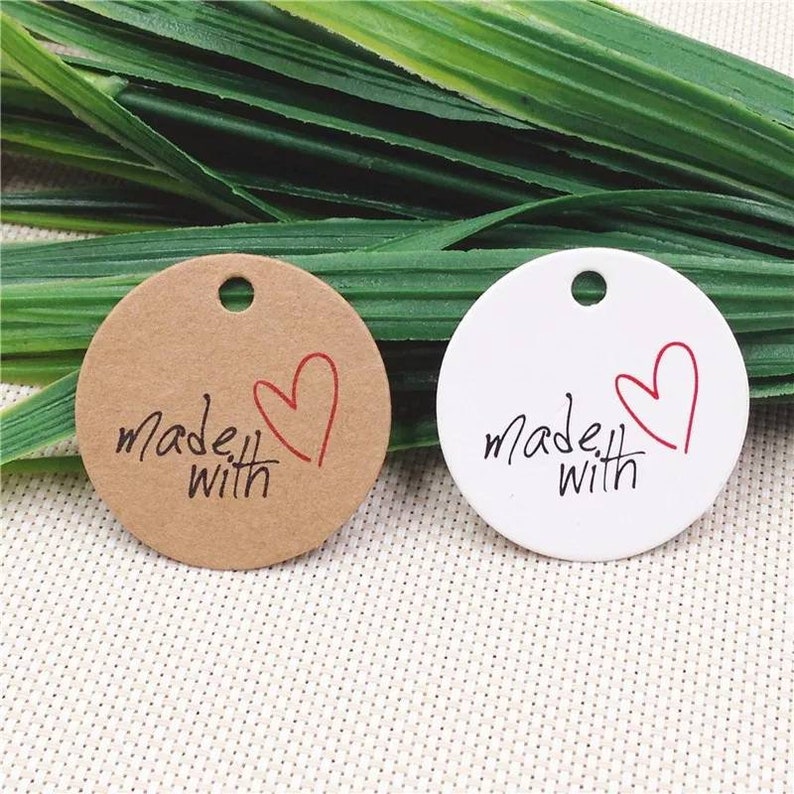 May include: Two round gift tags, one brown and one white, with a red heart and the text "made with" in black.