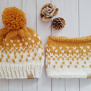 May include: A yellow and white knit hat with a pom pom on top and a matching knit neck warmer. Both items have a geometric pattern and a brown tag that says "Tundra Knits".