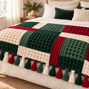 May include: A crochet blanket featuring a waffle stitch pattern in a color-blocked design of dark green, cream, and deep red squares. The bottom edge is finished with a row of alternating cream, dark green, and red yarn tassels.