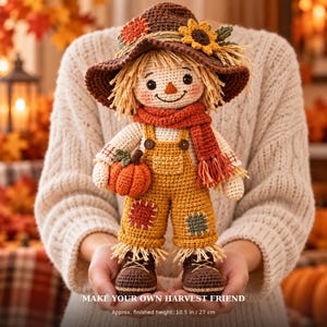 May include: A crocheted scarecrow doll wearing a brown hat with a sunflower, a red scarf, and yellow overalls with patches. The doll holds a small orange pumpkin and has brown shoes. Text reads: MAKE YOUR OWN HARVEST FRIEND. Approx. finished height: 10.5 inches.
