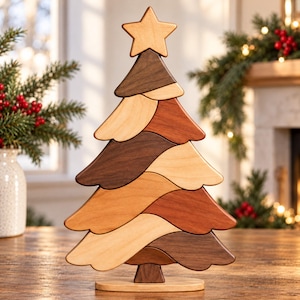 May include: A decorative wooden Christmas tree sculpture composed of layered, interlocking segments in varying shades of light, medium, and dark brown wood. The tree is topped with a five-pointed star and stands on a flat, oval wooden base.