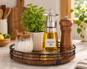 May include: A round wooden tray with a black metal railing holds a glass salt cellar with a wooden lid and spoon, a potted basil plant, a glass olive oil dispenser with a label reading Olive Oil, and a wooden pepper mill.