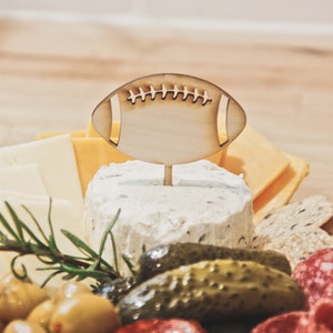 These football helmet party food picks are the perfect Game Day Decoration! Use them in your charcuterie board, as cupcake toppers, or place around! They are the perfect wood label for your Sports Theme Party Decor