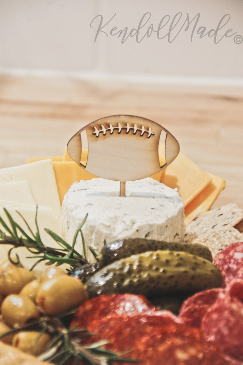 These football helmet party food picks are the perfect Game Day Decoration! Use them in your charcuterie board, as cupcake toppers, or place around! They are the perfect wood label for your Sports Theme Party Decor