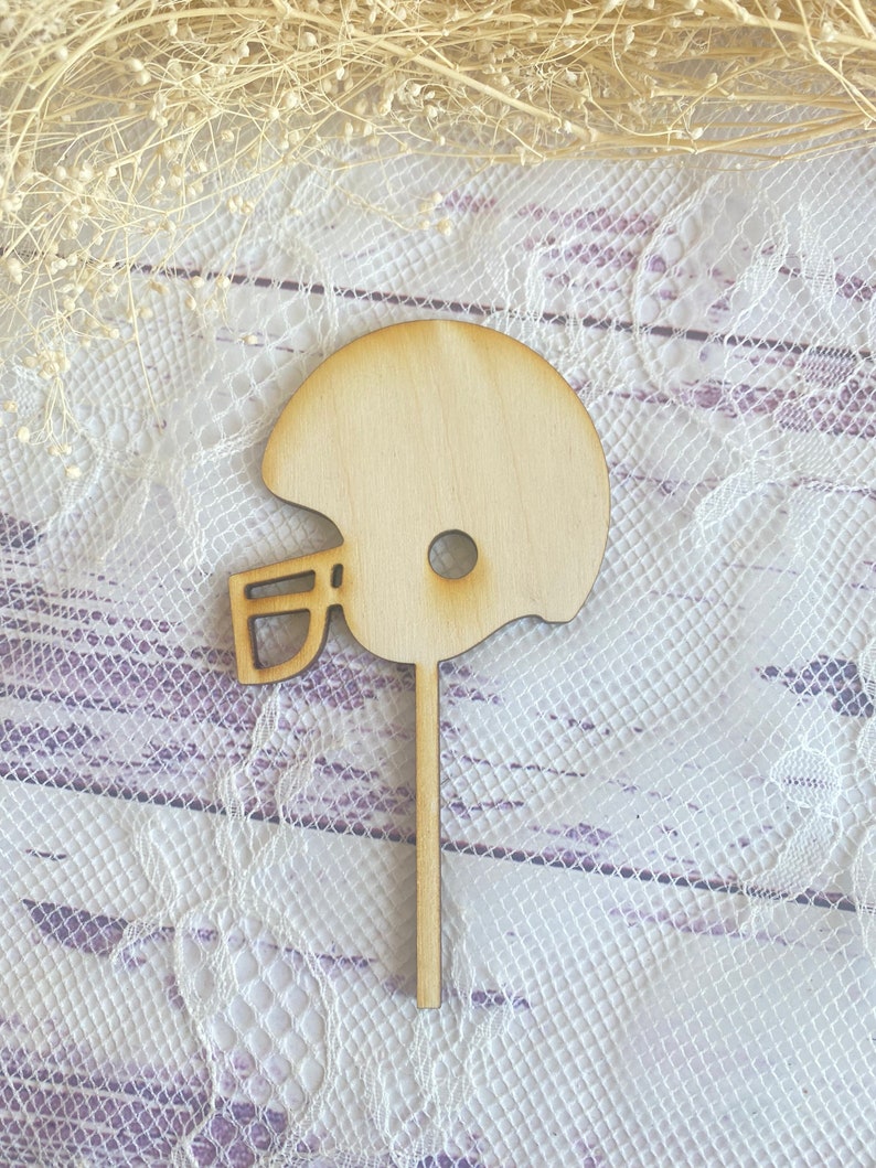 Pu&ograve; includere: Un ritaglio di legno di un casco da football americano, perfetto per decorare torte o progetti di artigianato.