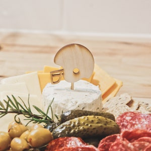 These football helmet party food picks are the perfect Game Day Decoration! Use them in your charcuterie board, as cupcake toppers, or place around! They are the perfect wood label for your Sports Theme Party Decor