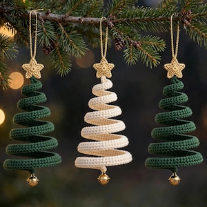 May include: Three spiral-shaped Christmas tree ornaments made of crocheted yarn. Two are dark green and one is cream-colored. Each ornament features a small gold-colored crocheted star at the top and a tiny gold-colored metal bell at the base.