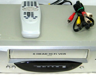May include: Silver Sanyo 4-Head Hi-Fi VCR with a remote control and AV cables. The VCR has buttons for power, stop, and eject. The remote is white with multiple buttons. The AV cables have red, yellow, and white connectors.