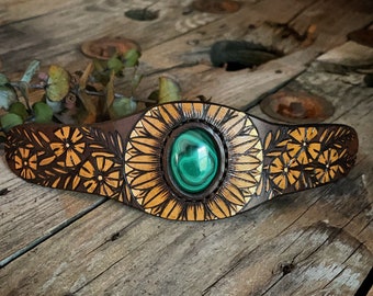 May include: A leather bracelet with a green malachite stone set in a gold-toned floral design.