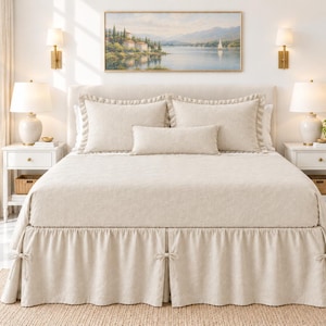 May include: A beige bed skirt featuring a ruffled design with decorative fabric ties at the corners and center pleats. The bed skirt is made of a solid-colored fabric and is positioned beneath a matching beige bedspread and pillows.