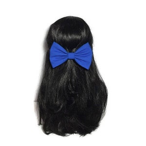 May include: A large blue fabric bow hair clip. The bow is tied in a classic shape with a center knot.