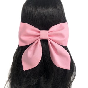 Puede incluir: Un gran lazo de tela rosa para el pelo. El lazo est&aacute; atado en una forma cl&aacute;sica con dos lazos y un nudo central.