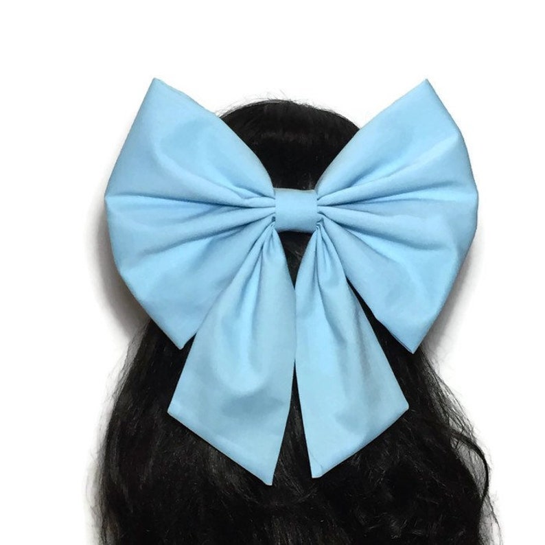 May include: A large, sky blue bow made of fabric. The bow is tied in a classic style with two long tails.