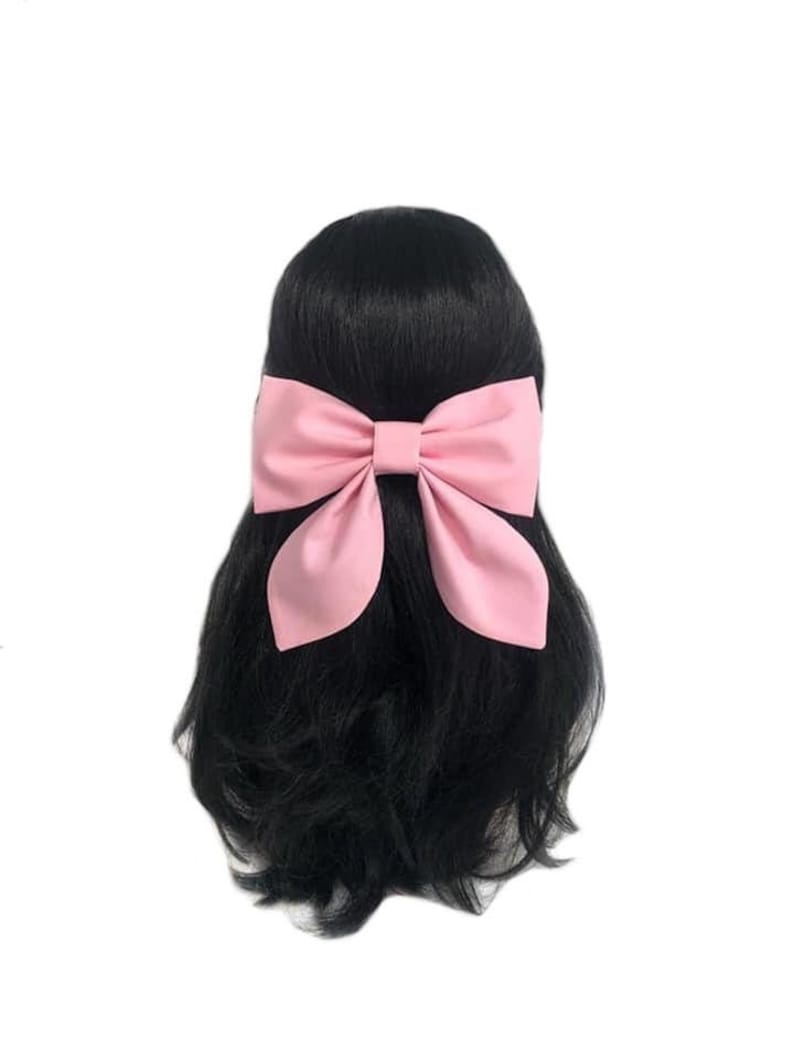 Puede incluir: Una gran pinza para el pelo con lazo rosa. El lazo est&aacute; hecho de tela y est&aacute; atado en un nudo grande y suelto. El lazo est&aacute; unido a una pinza que se puede usar para sujetar el lazo en el pelo.