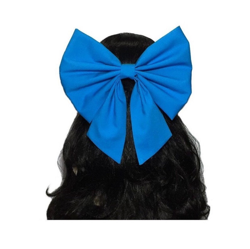 May include: A large, bright blue bow made of fabric. The bow is tied in a classic style and is worn in a person's hair.