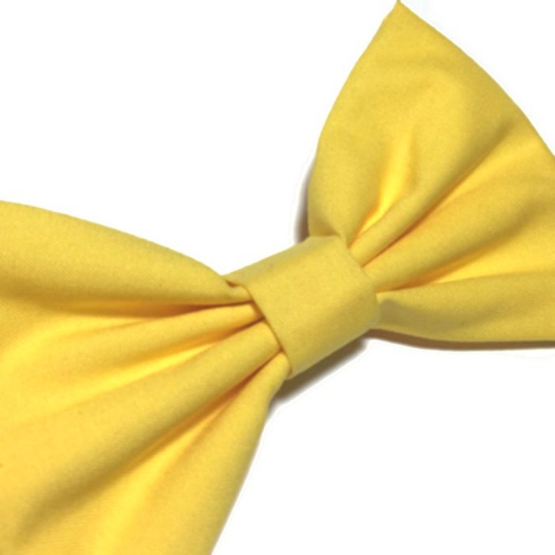 May include: A large yellow fabric bow. The bow is made of a soft, smooth fabric and has a simple, elegant design.