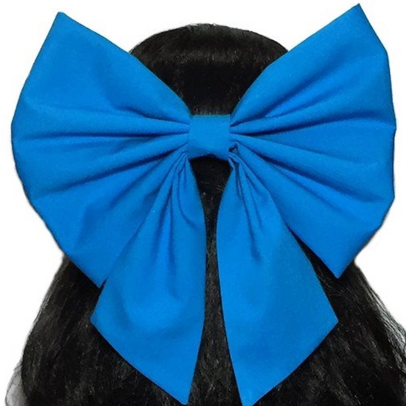 May include: A large, bright blue bow made of fabric. The bow is tied with a long tail and is suitable for use as a hair accessory.