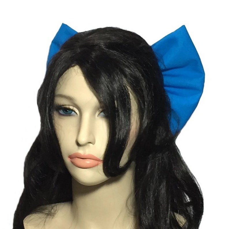 May include: A pair of blue fabric hair bows with ruffled edges. The bows are worn on a mannequin with long black hair.