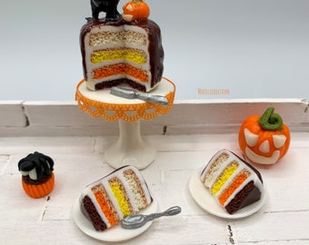 Miniature d’Halloween layer cake présenté sur un stand à gâteaux, petites parts de gâteau et boissons aux couleurs assorties