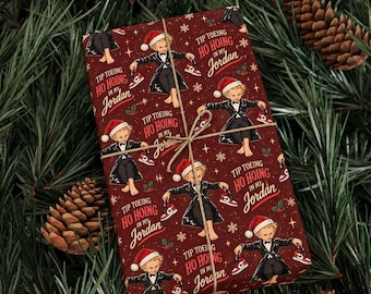 May include: Dark red wrapping paper featuring a repeating pattern of a blonde child in a black tuxedo and Santa hat, holding red and white sneakers. The text reads Tip Toeing Ho Hoing In My Jordan, accented with small white stars and holly.