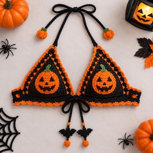 Pode incluir: Um top halter de crochê preto e laranja com duas copas triangulares apresentando motivos de abóbora. O top possui laços de crochê pretos com pequenos pingentes de abóbora laranja no pescoço e pingentes de morcego pretos na frente.