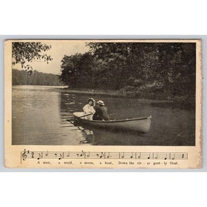 May include: Vintage black and white postcard depicting a couple in a rowboat on a calm lake. The image includes musical notation and the text "A man, a maid, a moon, a boat, Down the river gently float."