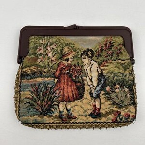 May include: A vintage tapestry purse with a brown clasp. The tapestry depicts two children in a garden setting, with a girl in a red dress and a boy in blue shorts. The purse has a detailed, textured design with a brown border.