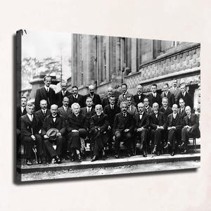 May include: A black and white canvas print depicting the 1927 Solvay Conference, featuring a large group of scientists in formal suits and dresses posed in rows before a stone building. The composition captures numerous individuals.