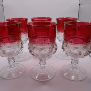 May include: Six vintage wine glasses with ruby red bowls and clear, patterned bases. The glasses have a classic design with a stem and a rounded foot. The red color is vibrant and eye-catching, perfect for a formal setting.