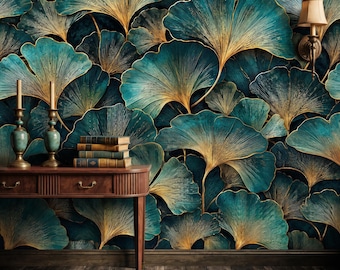 May include: A wooden console table with two candlesticks and a stack of three books stands against a wall covered in teal and gold ginkgo leaf wallpaper. A wall-mounted lamp is visible on the right side above the table.
