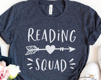 May include: A heather navy blue t-shirt with a white graphic that says "Reading Squad" with an arrow and heart.