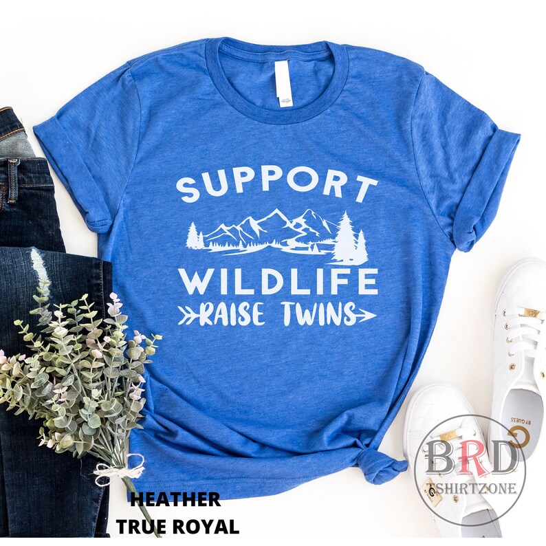 Puede incluir: Camiseta azul con texto blanco que dice "Support Wildlife Raise Twins" con un gr&aacute;fico de monta&ntilde;a y pino.