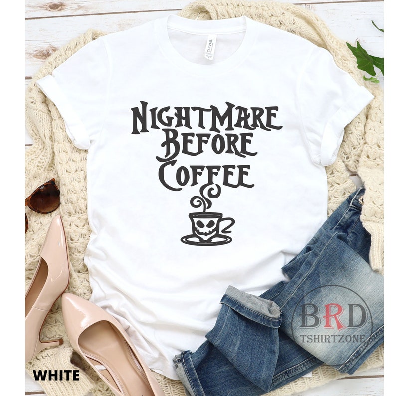 May include: White t-shirt with the text "NIGHTMARE BEFORE COFFEE" in a gothic font, featuring a skull-faced coffee cup graphic. The shirt is displayed with jeans, shoes, and sunglasses.