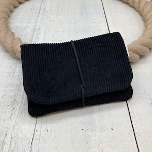 Könnte beinhalten: Eine schwarze Cordtasche mit einem schwarzen Gummibandverschluss.