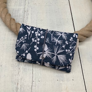 Könnte beinhalten: Eine dunkelblaue Stofftasche mit einem weißen Blumenmuster und einem grauen Kordelzug. Die Tasche hat ein kleines weißes Etikett mit dem Wort "JIFERSIE" darauf.