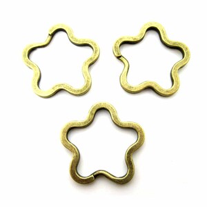 Può includere: Tre portachiavi a forma di stella in metallo color oro antico.