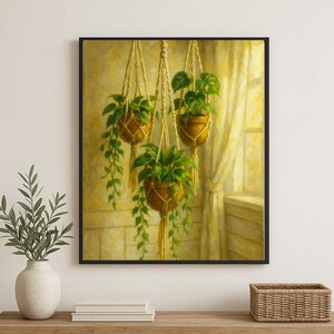 以下が含まれることがあります： 額縁に入った絵画には、垂れ下がる緑の植物が入った3つの吊り下げプランターが描かれています。茶色のプランターはマクラメハンガーで吊り下げられています。背景には、柔らかな黄色い光に包まれた透明なカーテンのある窓があります。