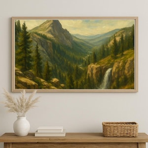Könnte beinhalten: Gerahmtes Landschaftsgemälde, das eine Bergkette mit einem Wasserfall zeigt. Das Kunstwerk zeigt grüne Bäume, felsiges Gelände und einen hellbraunen Holzrahmen. Das Gemälde erinnert an Natur und Ruhe. Der Rahmen ist ca. 76 cm breit.