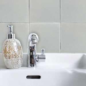 May include: A white ceramic bathroom sink with a chrome faucet and a decorative glass soap dispenser. The sink has two basins and a drain.