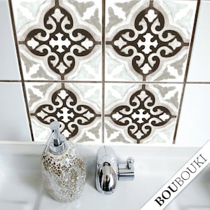 May include: Four decorative ceramic tiles with a white background and a brown intricate design. The tiles are arranged in a 2x2 grid. A white sink with a silver soap dispenser and a silver faucet is in the foreground. The text "BOUBOUKI" is in the bottom right corner of the image.