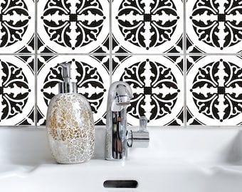 Puede incluir: Un lavabo de baño blanco con un grifo cromado y un dispensador de jabón dorado. El lavabo está colocado contra un salpicadero de azulejos con un patrón blanco y negro.