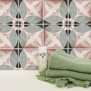 May include: A set of pink and black patterned ceramic tiles with a green waffle weave towel and a bottle of olive oil soap.