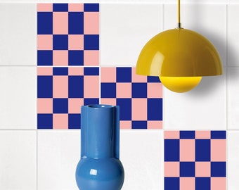 Könnte beinhalten: Drei rosa und blaue karierten Fliesen an einer weißen gekachelten Wand mit einer blauen Keramikvase und einer gelben Pendelleuchte.