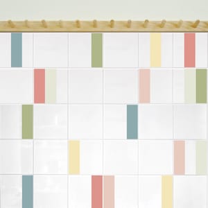 Könnte beinhalten: Weiße quadratische Fliesen mit vertikalen Streifen in verschiedenen Pastellfarben, darunter Blau, Rosa, Gelb und Grün. Über den Fliesen ist eine Garderobenleiste aus Holz angebracht. Minimalistisches und modernes Design.