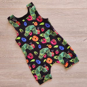 May include: Black sleeveless jumpsuit with a colorful print of caterpillars and fruit. The print features green caterpillars, red apples, and orange oranges.