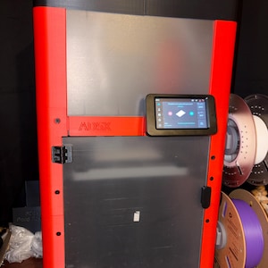 May include: A Flashforge AD5X 3D printer featuring a tall, rectangular frame with a vibrant red exterior and black accents. The front includes a translucent door, a digital touchscreen interface, and the text AD5X and FLASHFORGE.