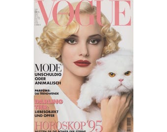May include: A magazine cover featuring a woman with blonde hair and red lipstick holding a white cat. The magazine is titled "Vogue" and the text on the cover reads "Mode: Unschuldig oder Animalisch, Parfums: Die Trendwende, Darling Tier: Liebesobjekt und Opfer, Horoskop '95, Nutzen Sie die Power der Sterne."